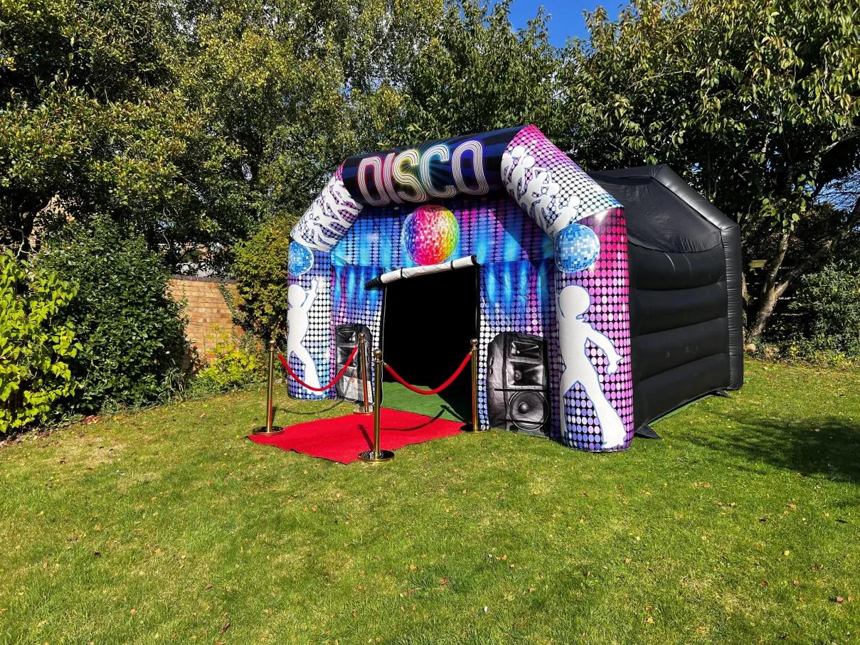 Disco inflatable with red carpet and ropes surrounded by trees