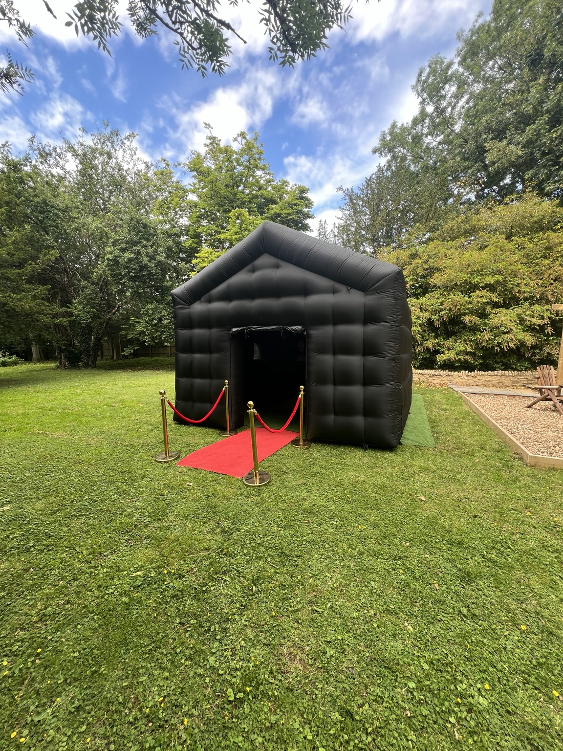 Black Ultimate nightclub with red carpet in a leafy garden